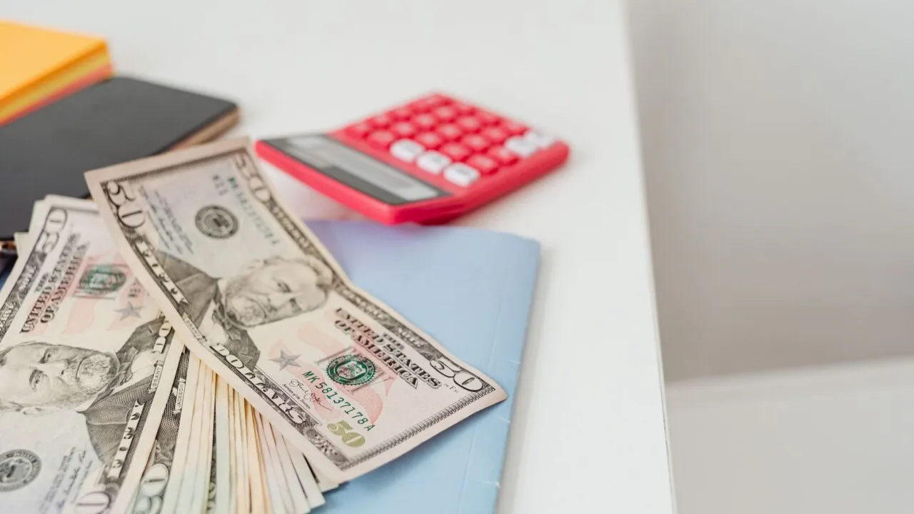 Caiet cu un plan de buget, un calculator și un pix pe o masă, la pregătirea primelor investiții