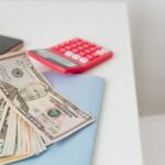 Caiet cu un plan de buget, un calculator și un pix pe o masă, la pregătirea primelor investiții