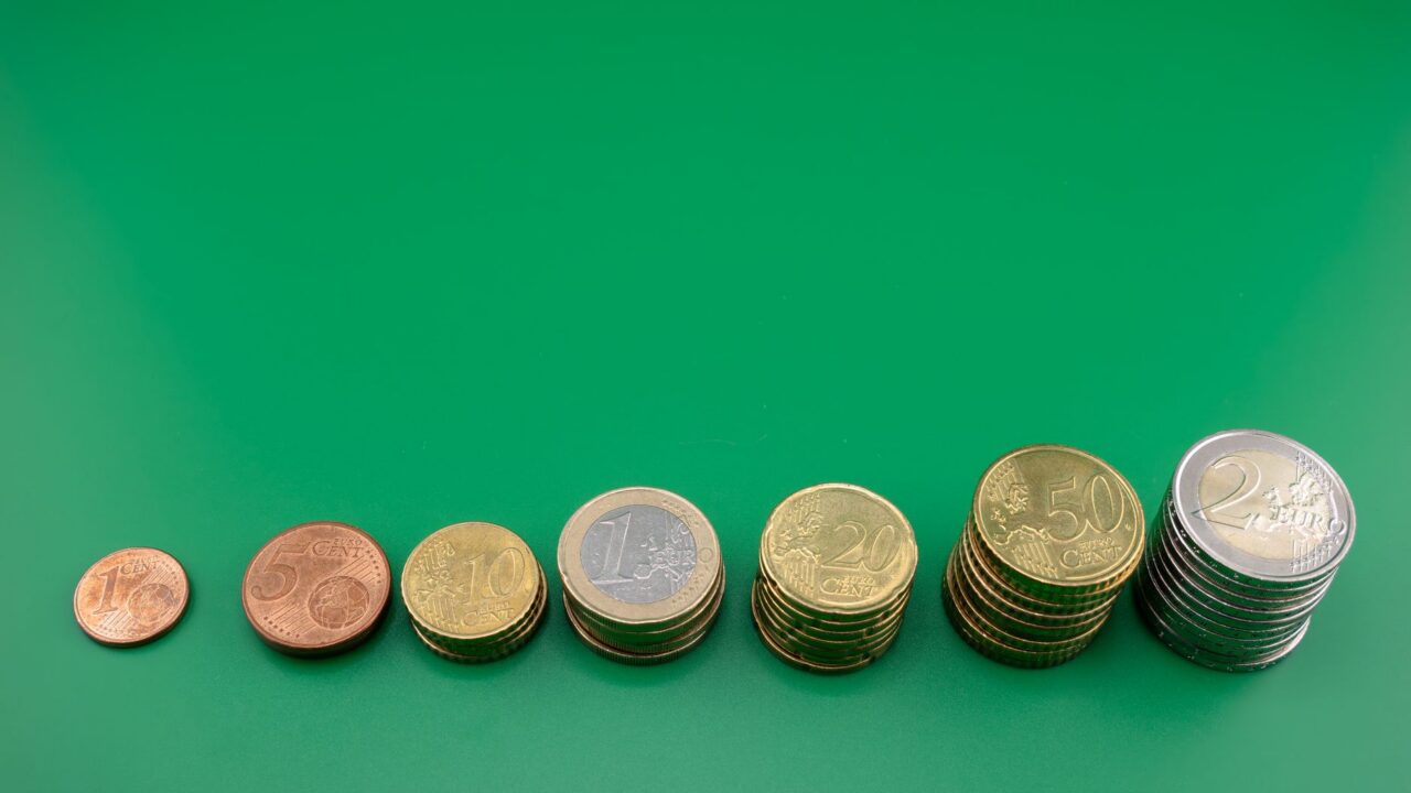 Monede așezate în coloane din ce în ce mai înalte pe o masă, simbol al economisirii constante